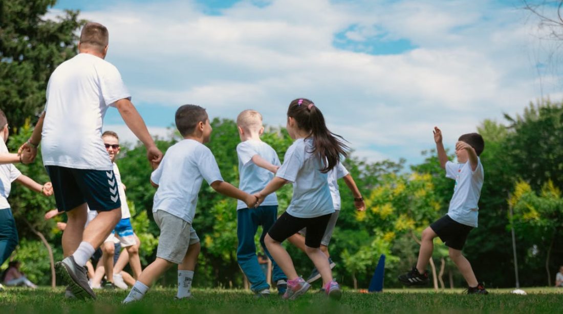 Group of children having fun and playing games together in a sunny park.