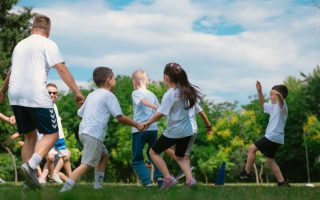 Group of children having fun and playing games together in a sunny park.
